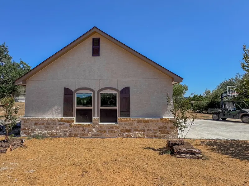 Custom stucco and stone outbuilding with arched windows