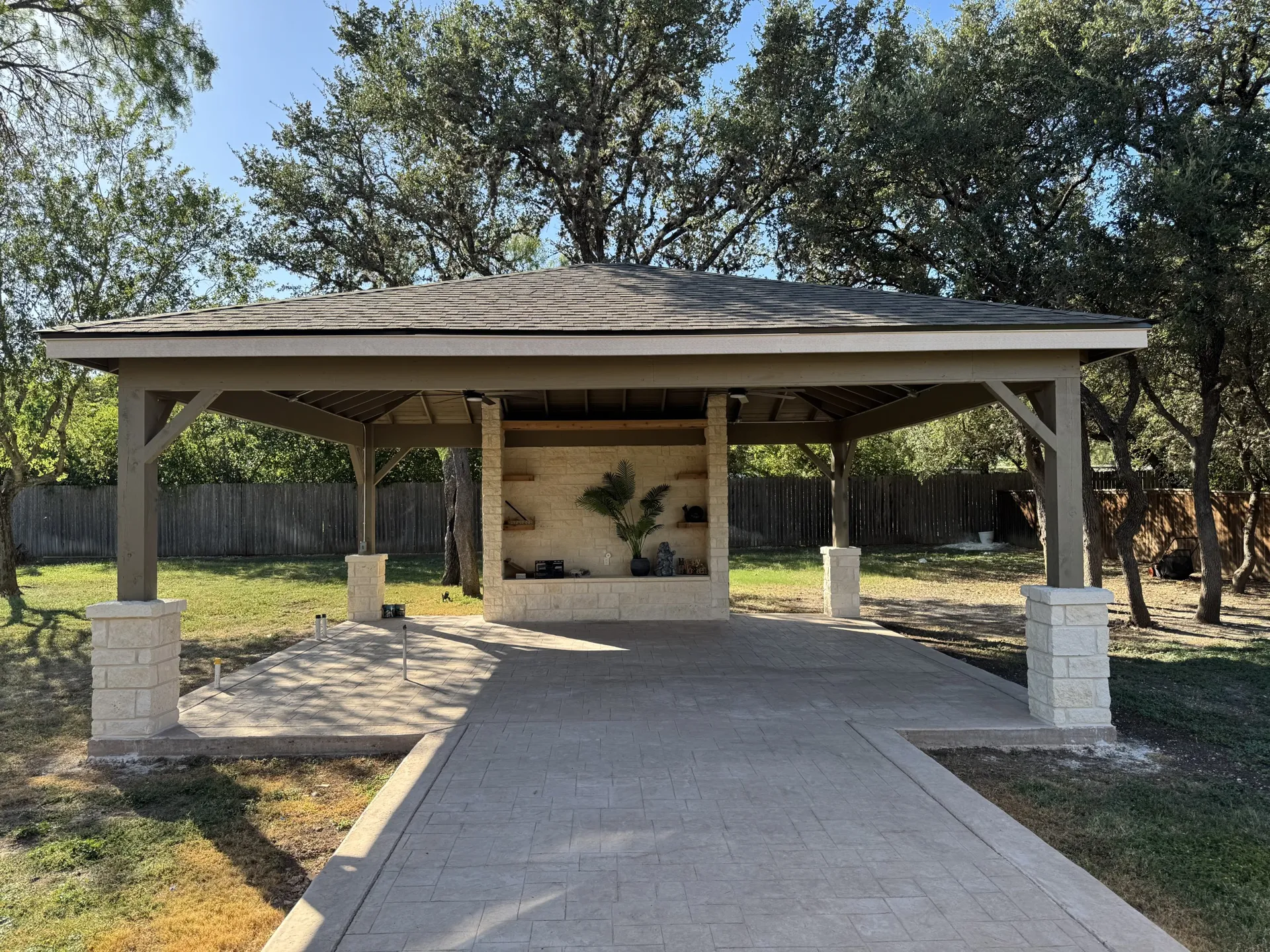 Hip-roof carport with stone columns and paver driveway