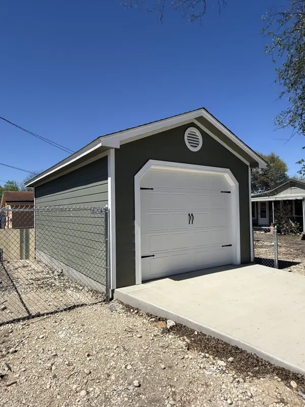 Deep green single-bay garage with carriage-style door