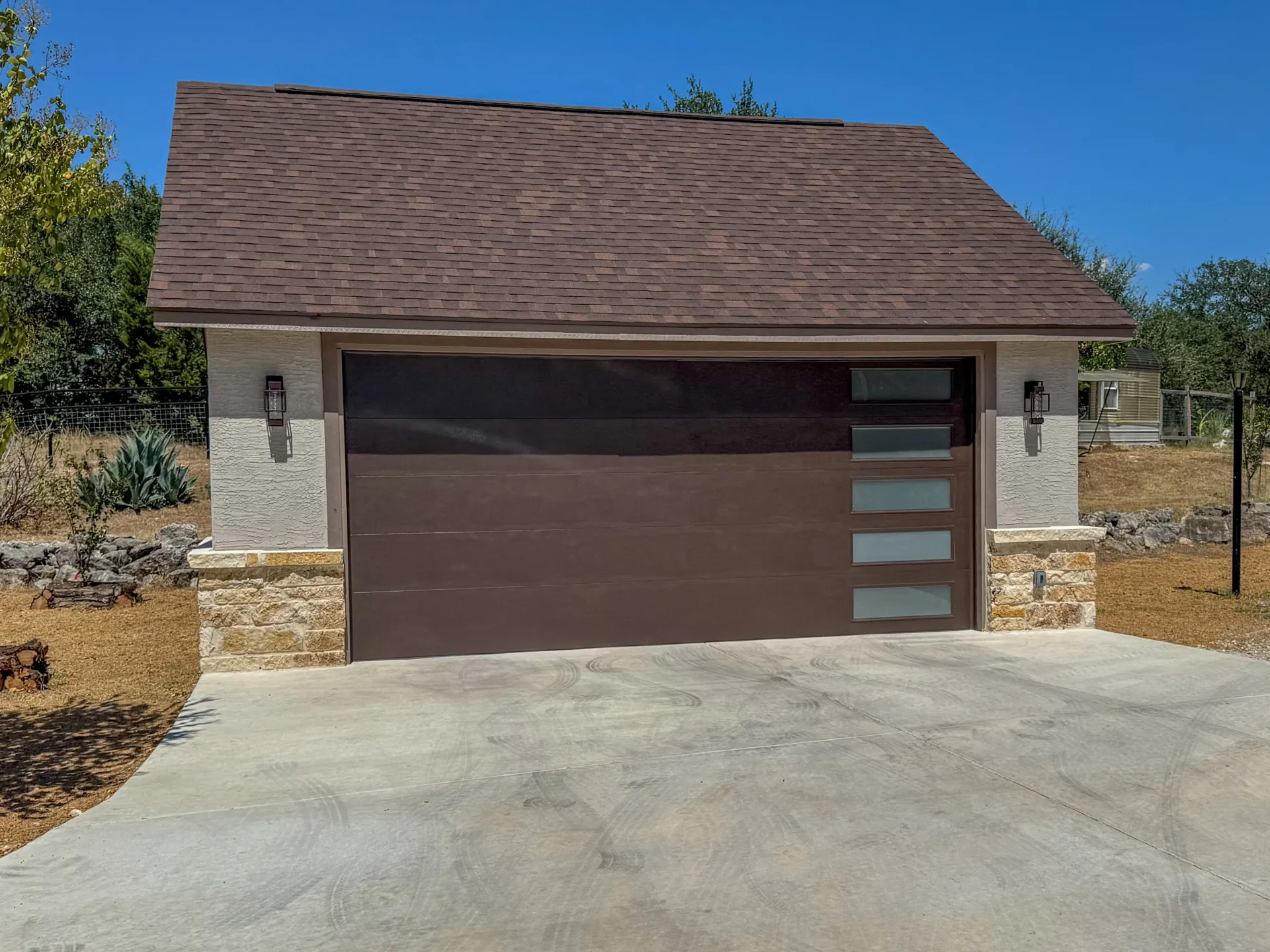 Modern glass-panel garage door with white brick and stone
