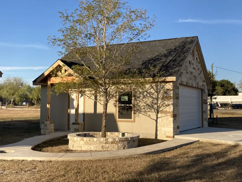 Stone and stucco garage with landscaped fire pit courtyard
