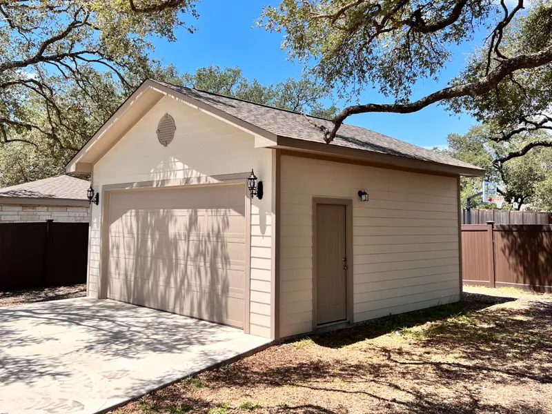 Tan detached garage built under mature oak trees