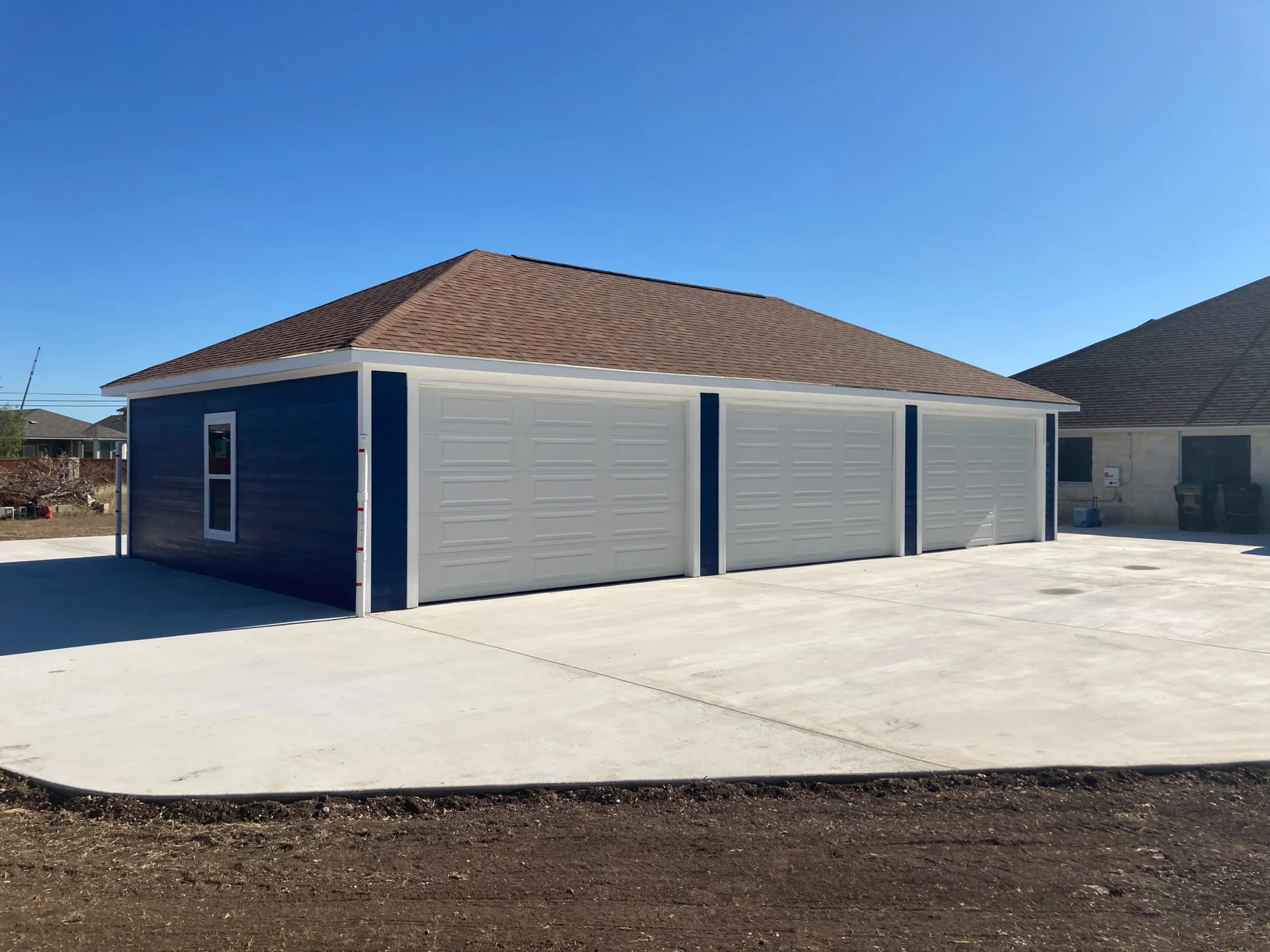 Navy three-bay detached garage on a fresh concrete slab