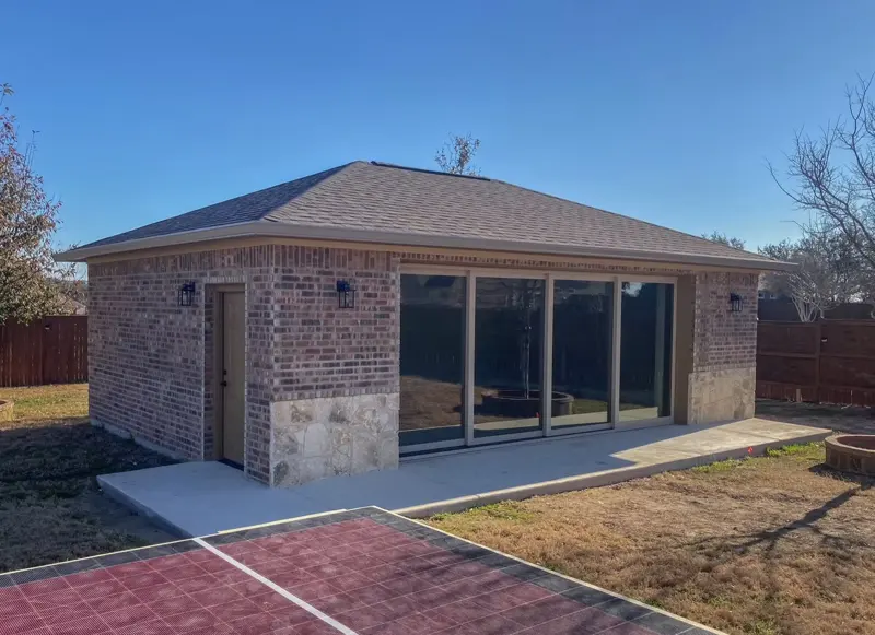 Brick home gym garage with glass doors beside a backyard sport court